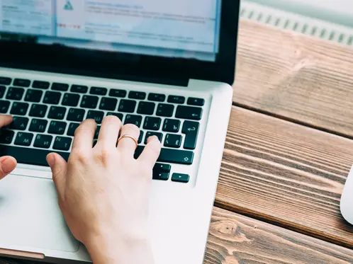 Woman working with laptop placed on wooden desk